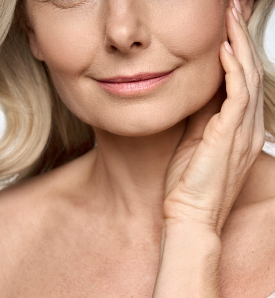 Face close up portrait of happy mid age 50 years old woman touching face with hand. Advertising of skin care anti wrinkle products for facial bottom part, lips, chin neck and decollete.