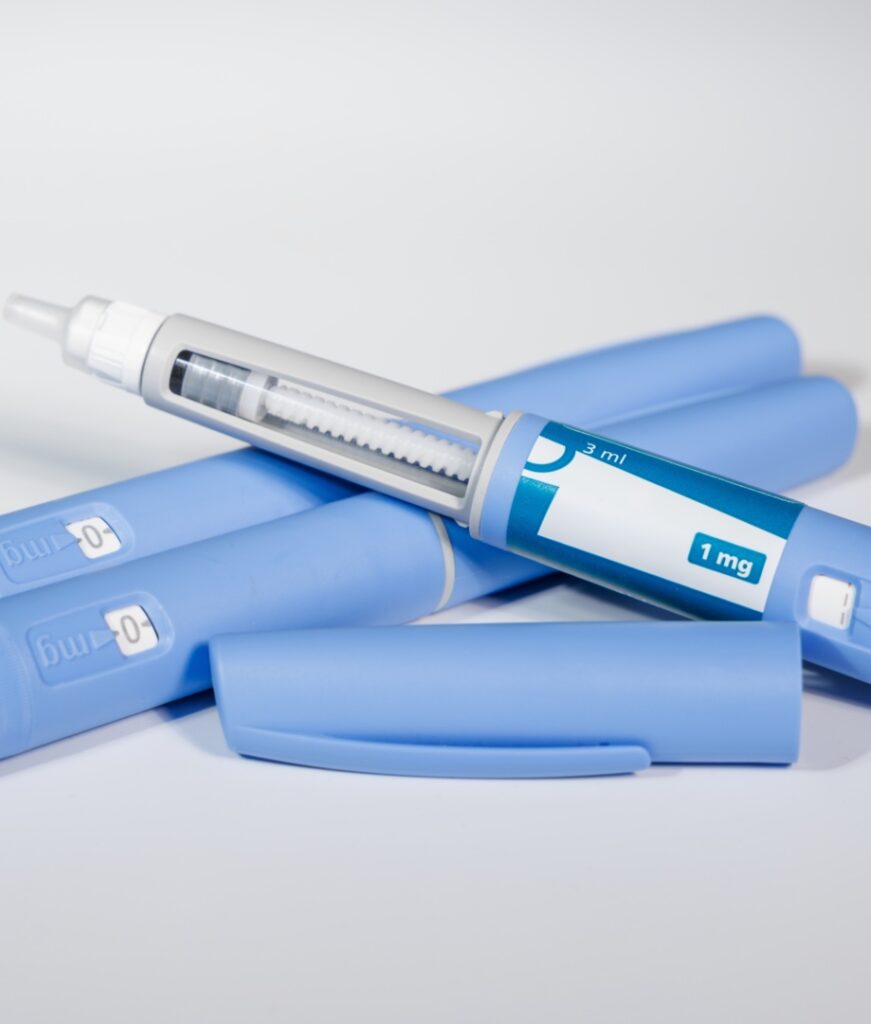 GLP-1 semaglutide injection pens with pills and measuring tape over white background illustrating health and prevention.
