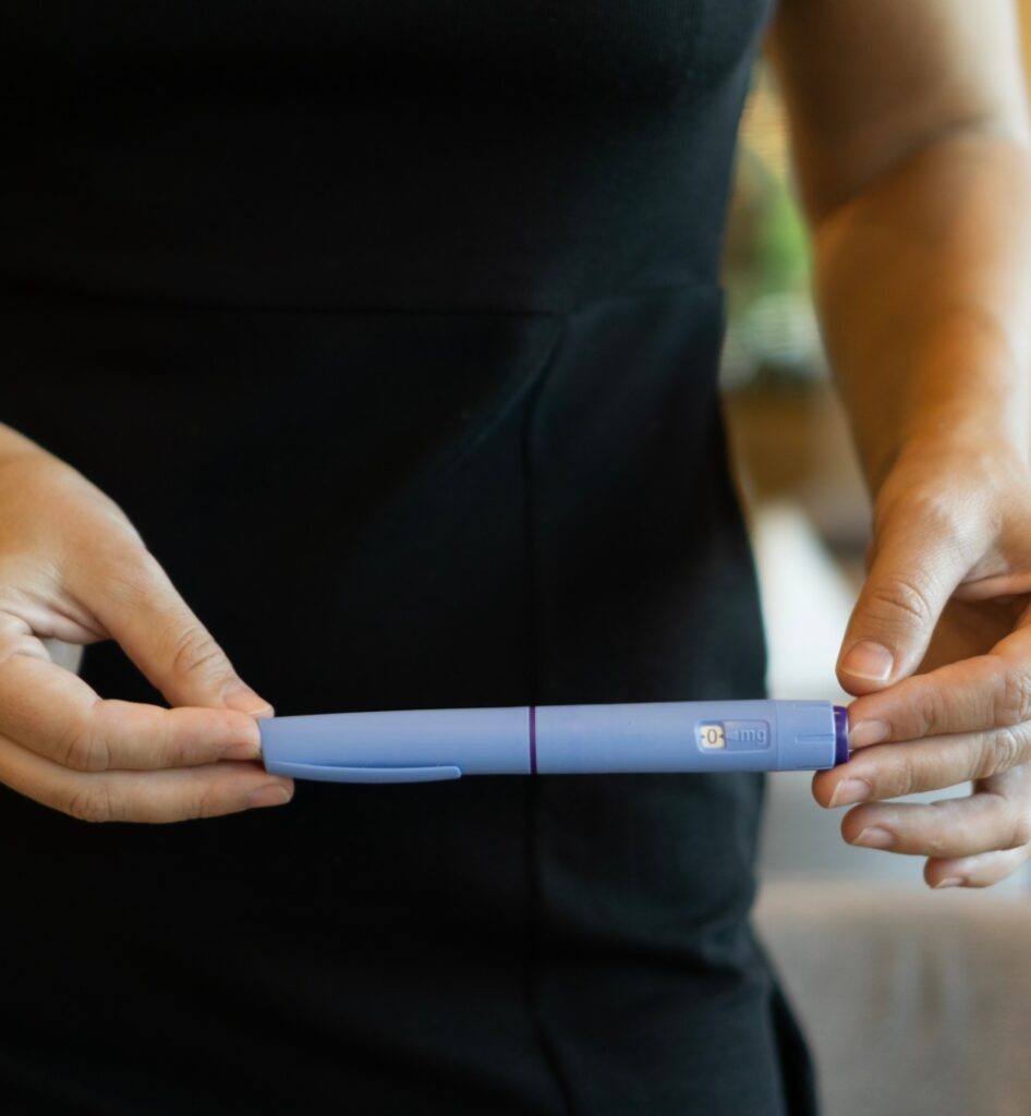 A woman in a black dress holding an ozempic pen, concept of medical treatment, modern healthcare, and weight loss solutions.